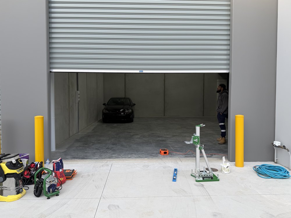 An open warehouse bay before the bollards went in, with the core drill and install gear on the ground